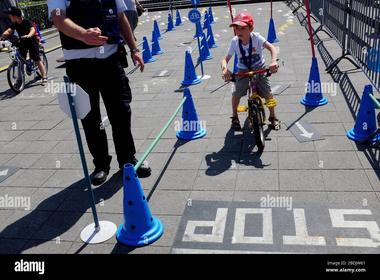 A child on children's bicycle in a traffic rule activity lead by police officer in Police force and Law enforcement show during Belgian National Day celebration. Brussels. Belgium Stock Photo