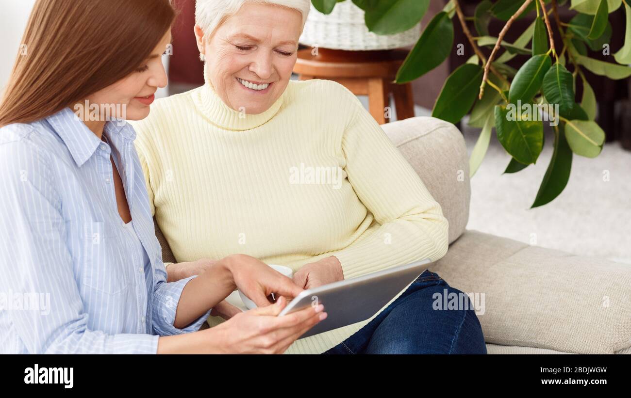 Daughter teaching mother using digital tablet at home Stock Photo