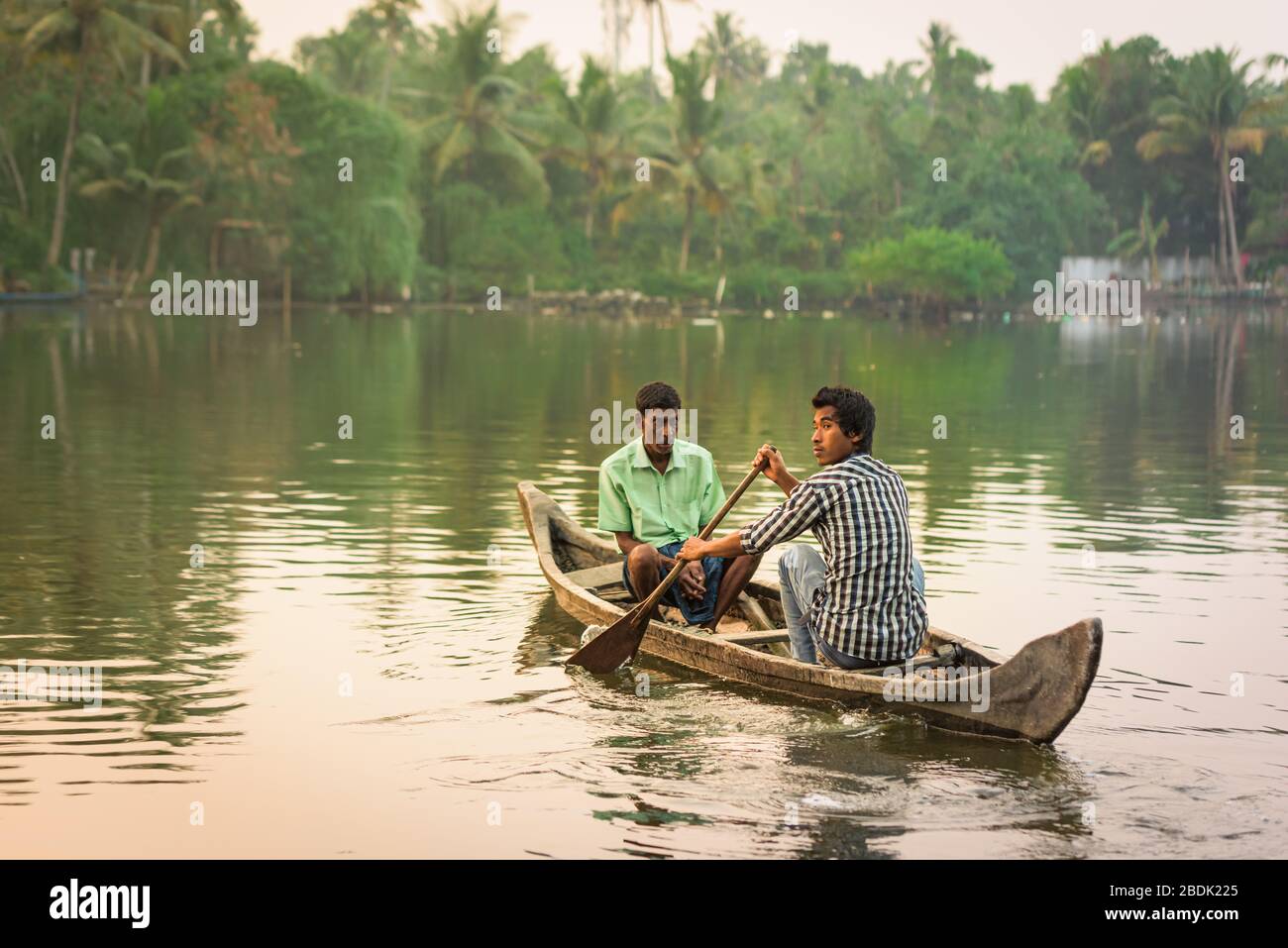 Eramalloor, India - 6 Fev 2017: Two men sit in a rowing boat crossing the Backwaters Lake in Eramalloor, Kerala, India Stock Photo