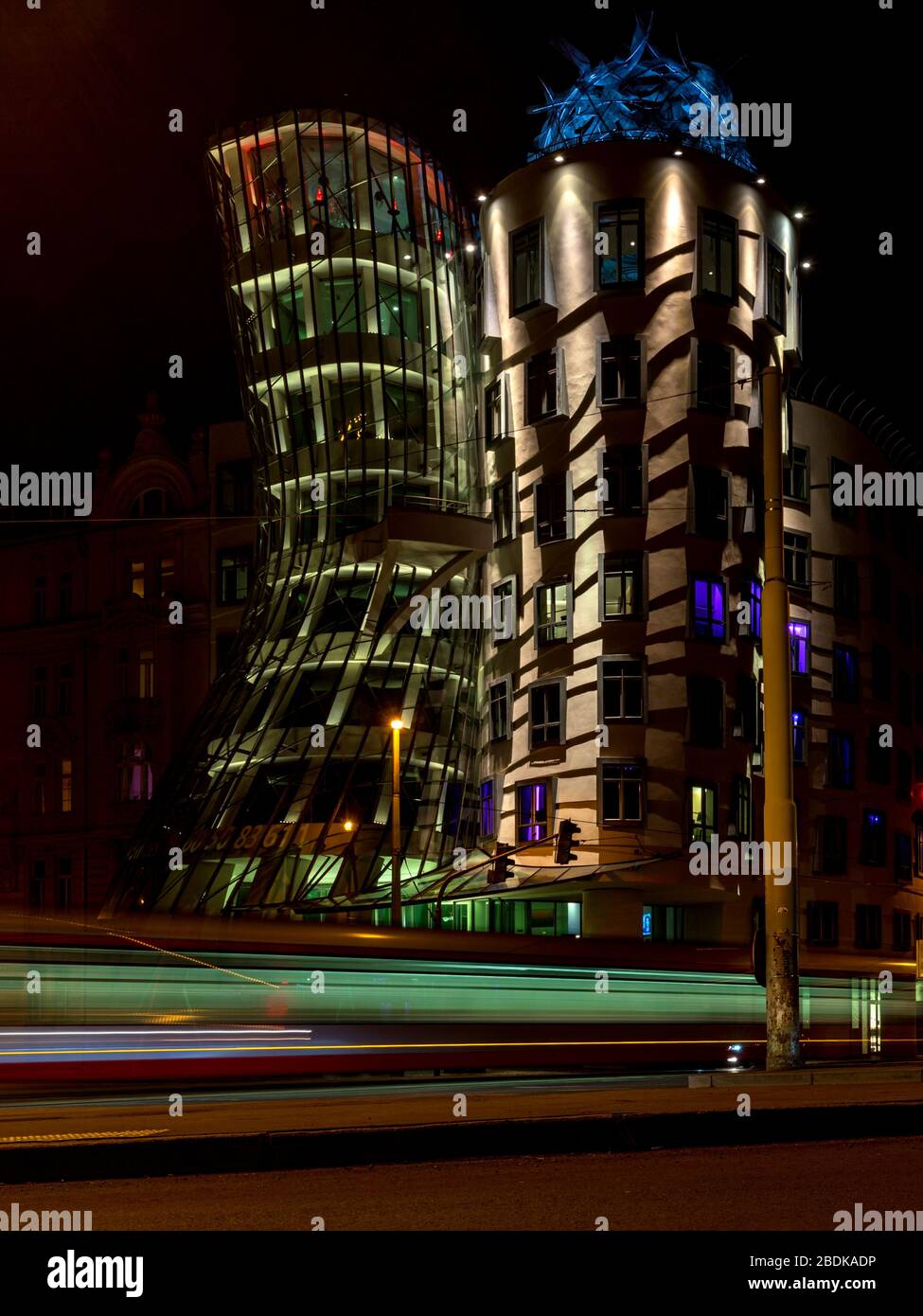 Light trails in front of the lit Dancing House building in Prague at night. The building was designed by the Croatian-Czech architect Vlado Milunic. Stock Photo