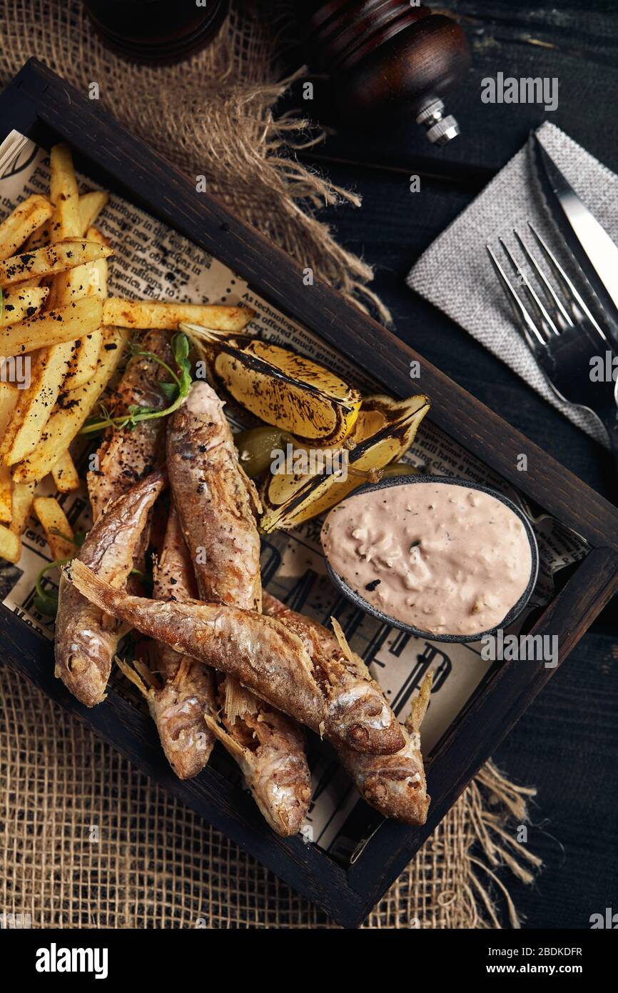 Fish and chips concept, traditional english food, fried fish and fries. Dark background, rustics style, wooden background, copy space. View from above Stock Photo