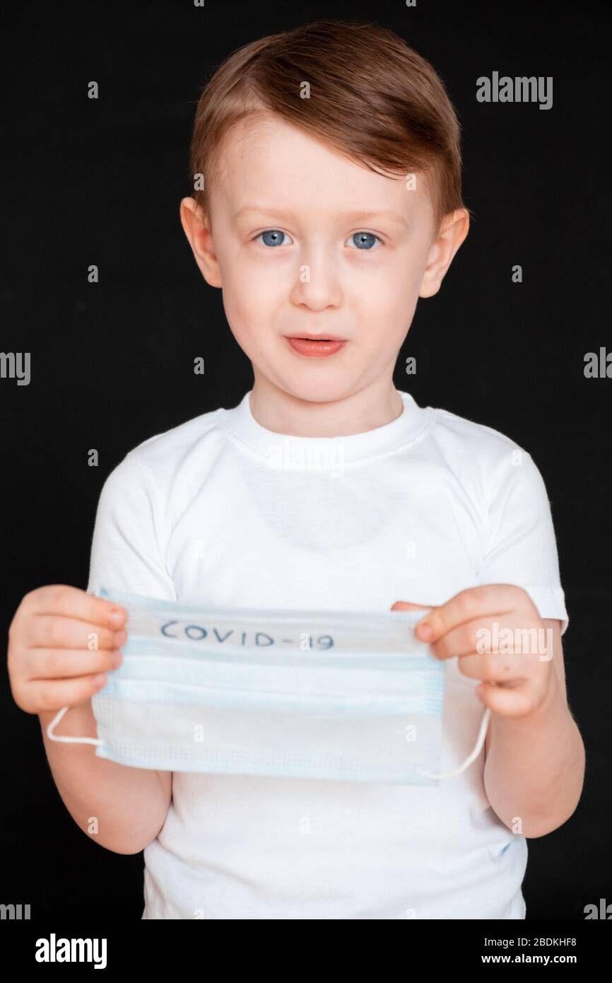 A little boy is holding a medical mask. Baby wears face masks covid19