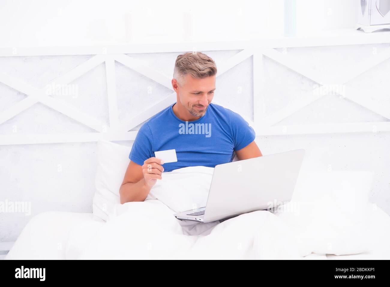 Payment and purchase. Online shopping. Work from home. Checking messages. Mature guy pajamas in bed. Businessman with computer. Hipster work on laptop. Bedroom rest. Remote job. Online communication. Stock Photo
