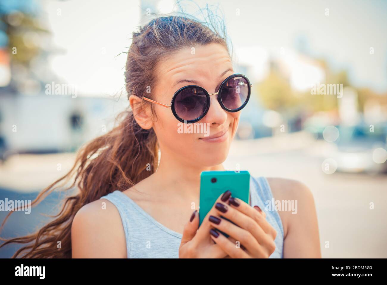 Closeup portrait upset sad, skeptical, unhappy, serious woman talking texting on phone displeased with conversation isolated outdoor background. Negat Stock Photo