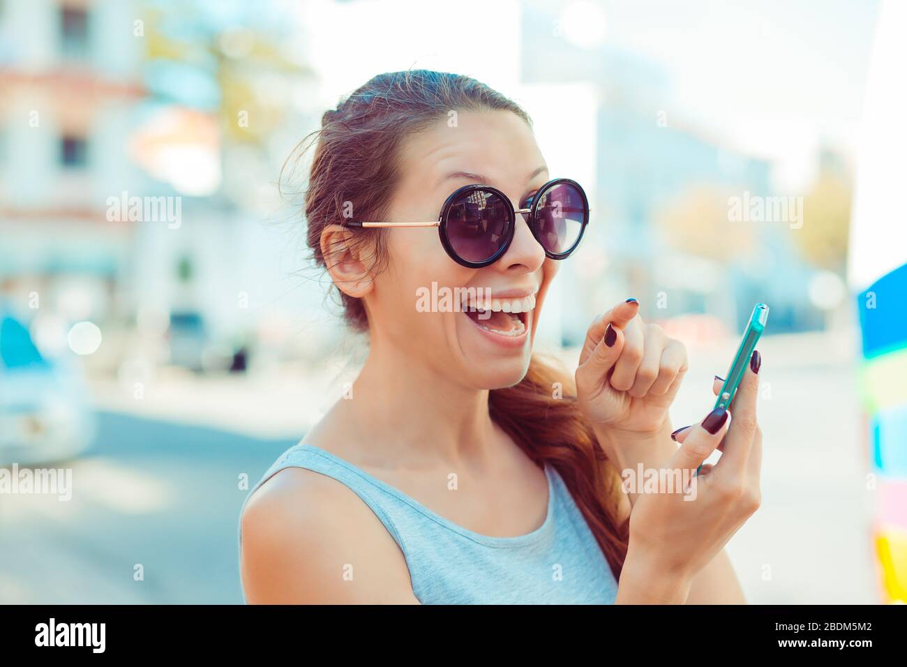 Excited funny young woman raising her finger about to push the button on her cell phone looking at you camera Stock Photo