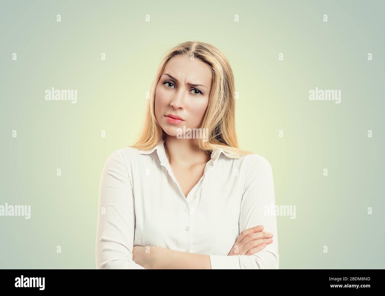 Closeup portrait, skeptical, serious senior young woman looking suspicious, disapproval on face, arms crossed folded, isolated white background. Negat Stock Photo