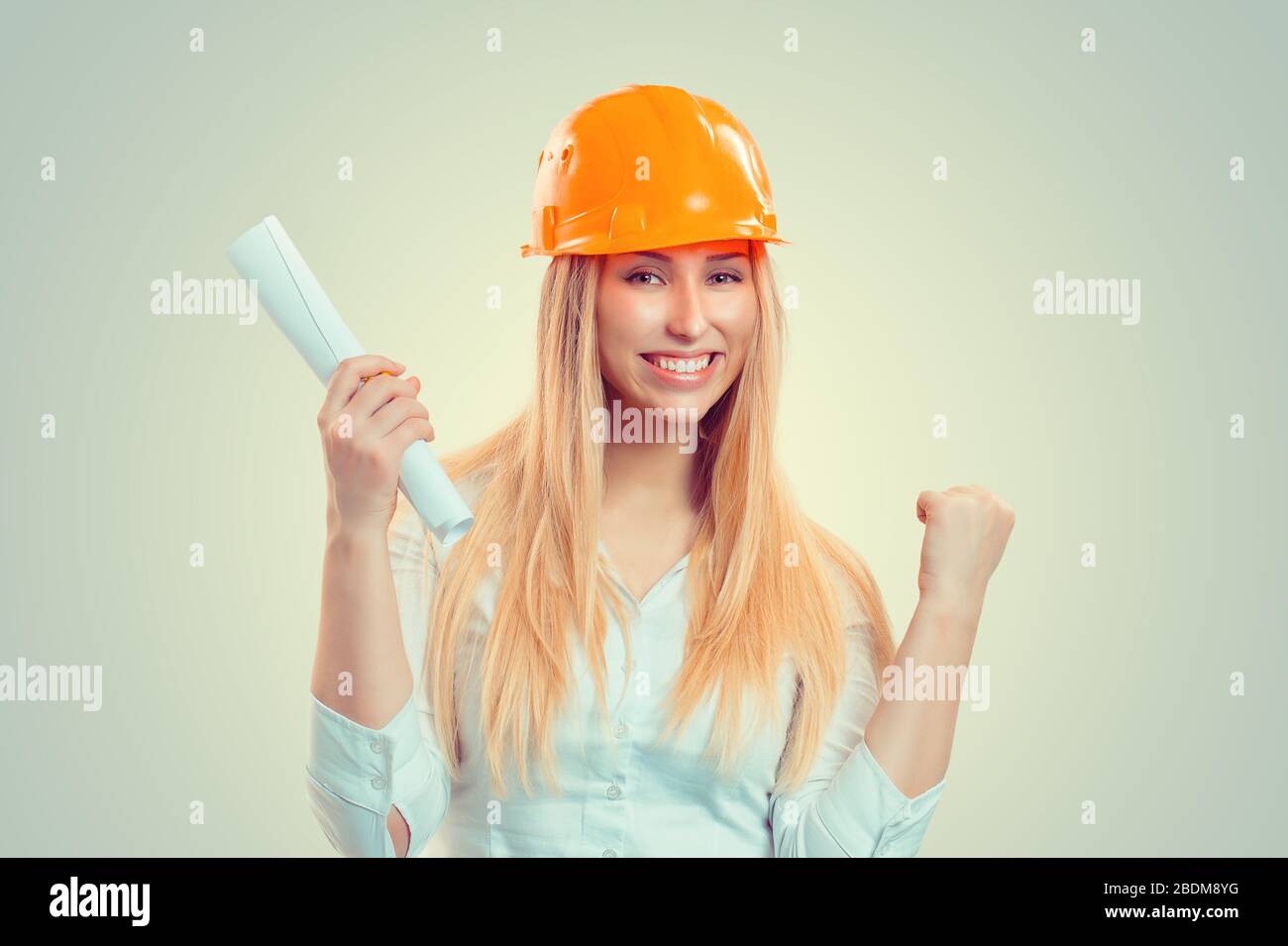 Architect successful. Closeup portrait happy smiling young construction woman yellow cap thumbs arm fist up celebrating win isolated green background. Stock Photo
