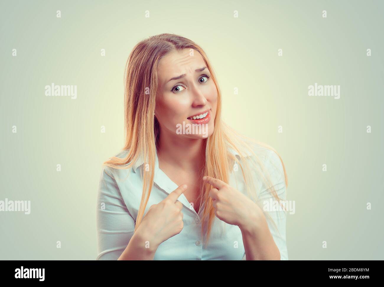 Me? Portrait of mad angry unhappy annoyed young woman getting mad asking question you talking to me, you mean me? really? Isolated on green yellow wal Stock Photo