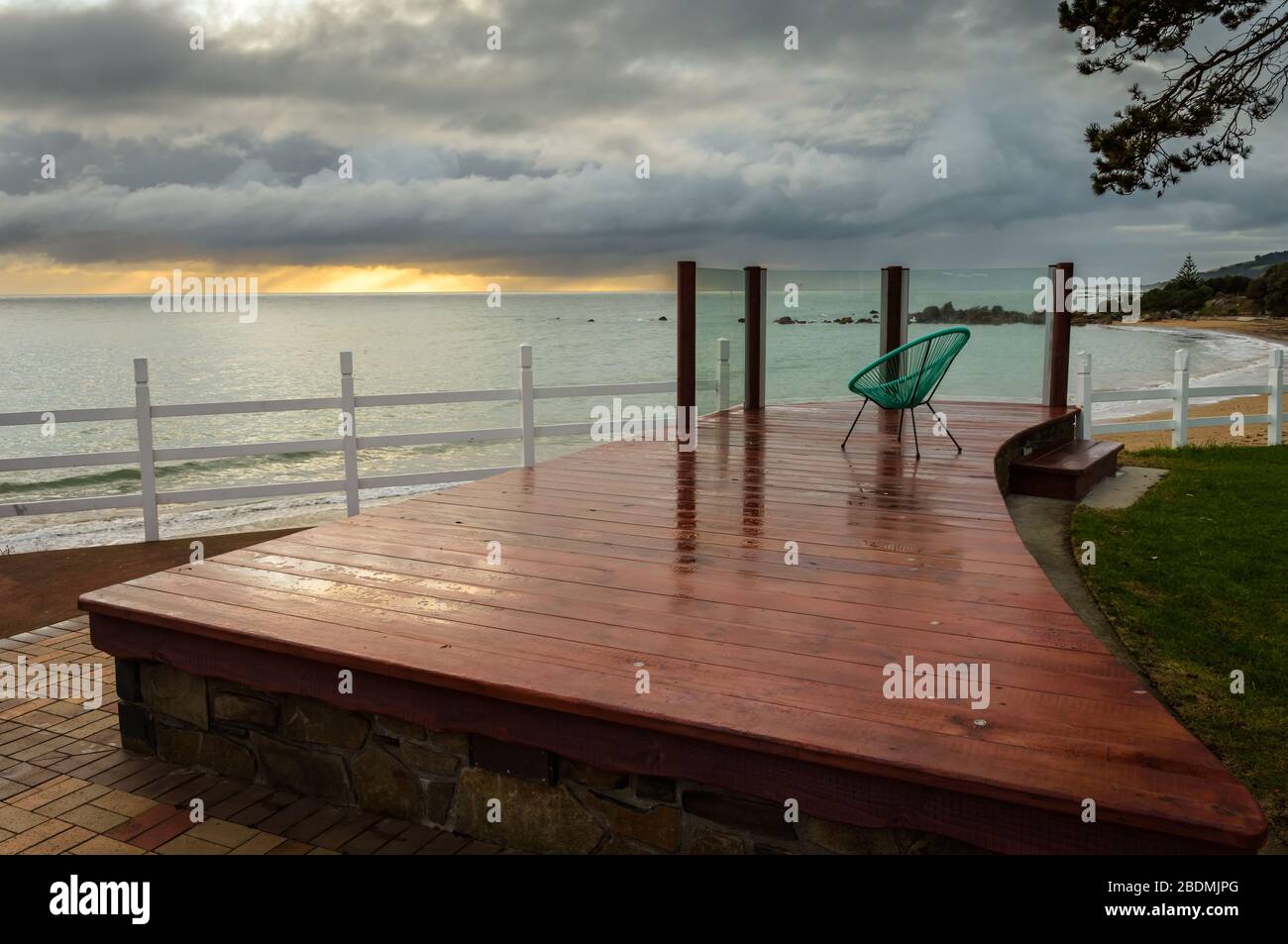A view from an artistic, tourist, viewing platform with 70's chair looking across Bass Strait as a storm is brewing on sunset in the town of Penguin. Stock Photo