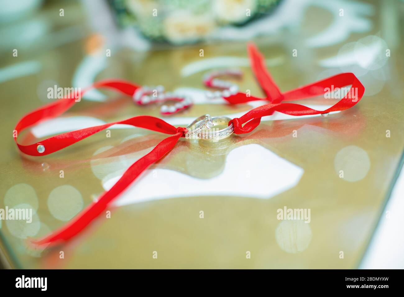 White wedding rings . flower bouquet selective focuse .Two silver wedding rings . Romantic and lovely wedding , macro . Red ribbon . Bride and groom Stock Photo