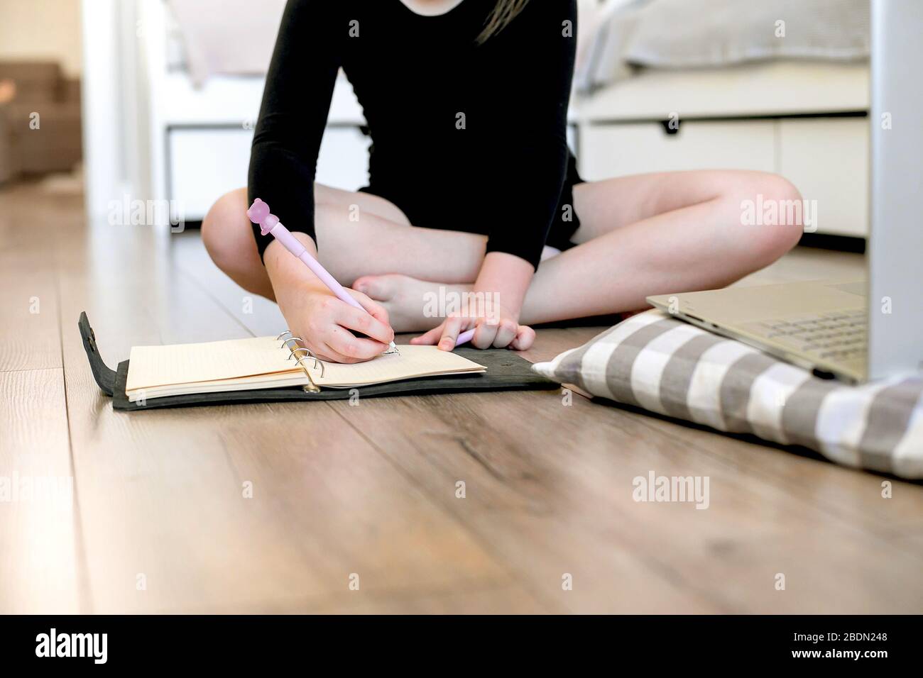 Young girl gymnast is engaged at home, writting in a notebook after training. Stay at home. Concept of self isolation, quarantine, online education. Stock Photo