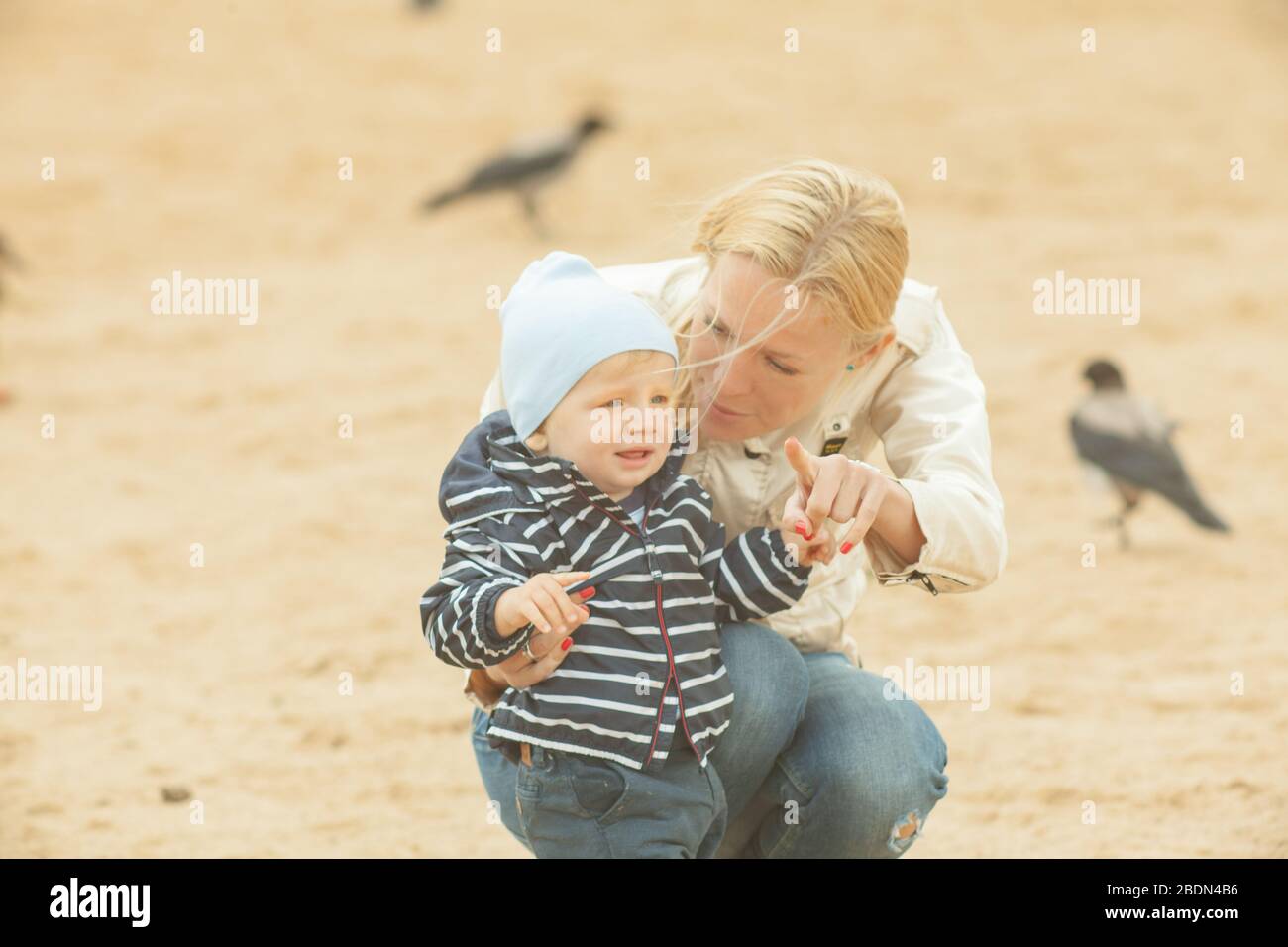 Single mother carrying and hugging a child outdoors near lake with natural yellow and white background Stock Photo