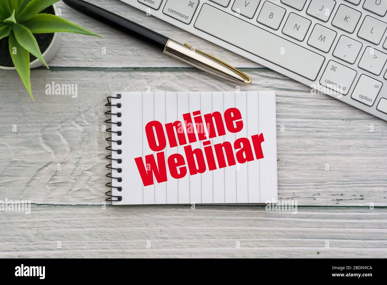 ONLINE WEBINAR text with decorative flower, fountain pen, keyboard and notepad on wooden background. Business and technology concept Stock Photo