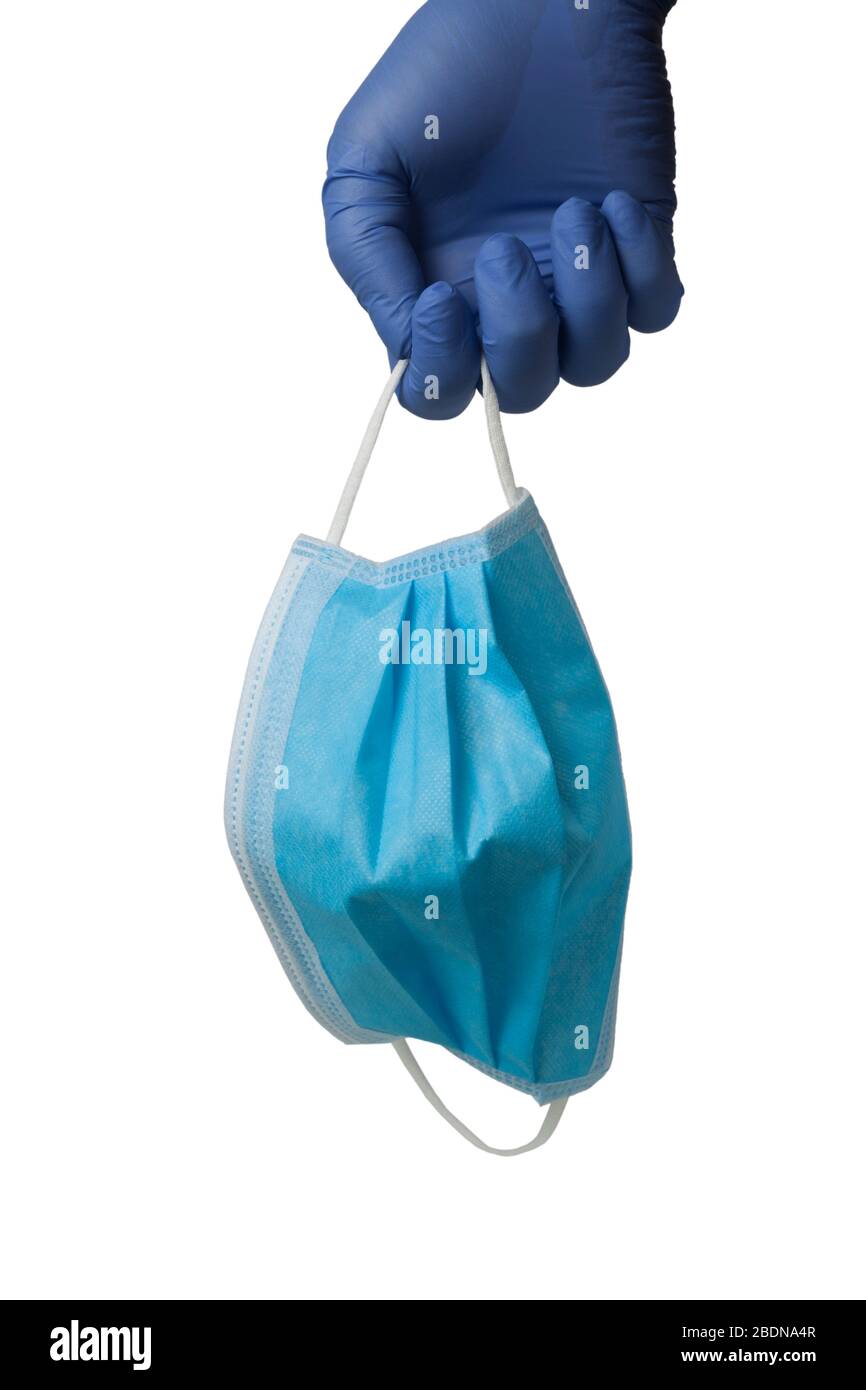 Surgical mask hanging from a gloved hand isolated on white background Stock Photo