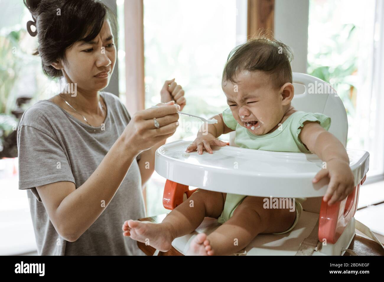 stress mother while feeding her baby at home Stock Photo