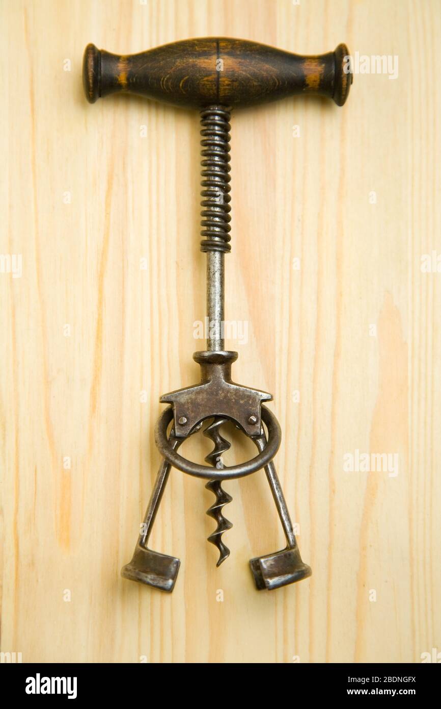 Simple old corkscrew lies on a wooden plate Stock Photo