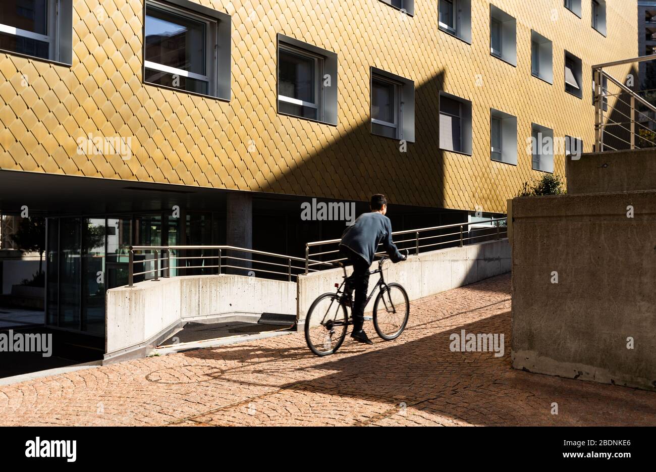 Boy on a bicycle makes a small climb in the midst of modern houses. Stock Photo