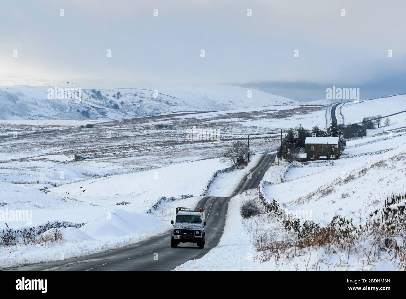 Snowy winter landscape (Land Rover Defender driving, country road, upland hills, snow covered farm fields) - near Greenhow, Yorkshire Dales England UK Stock Photo