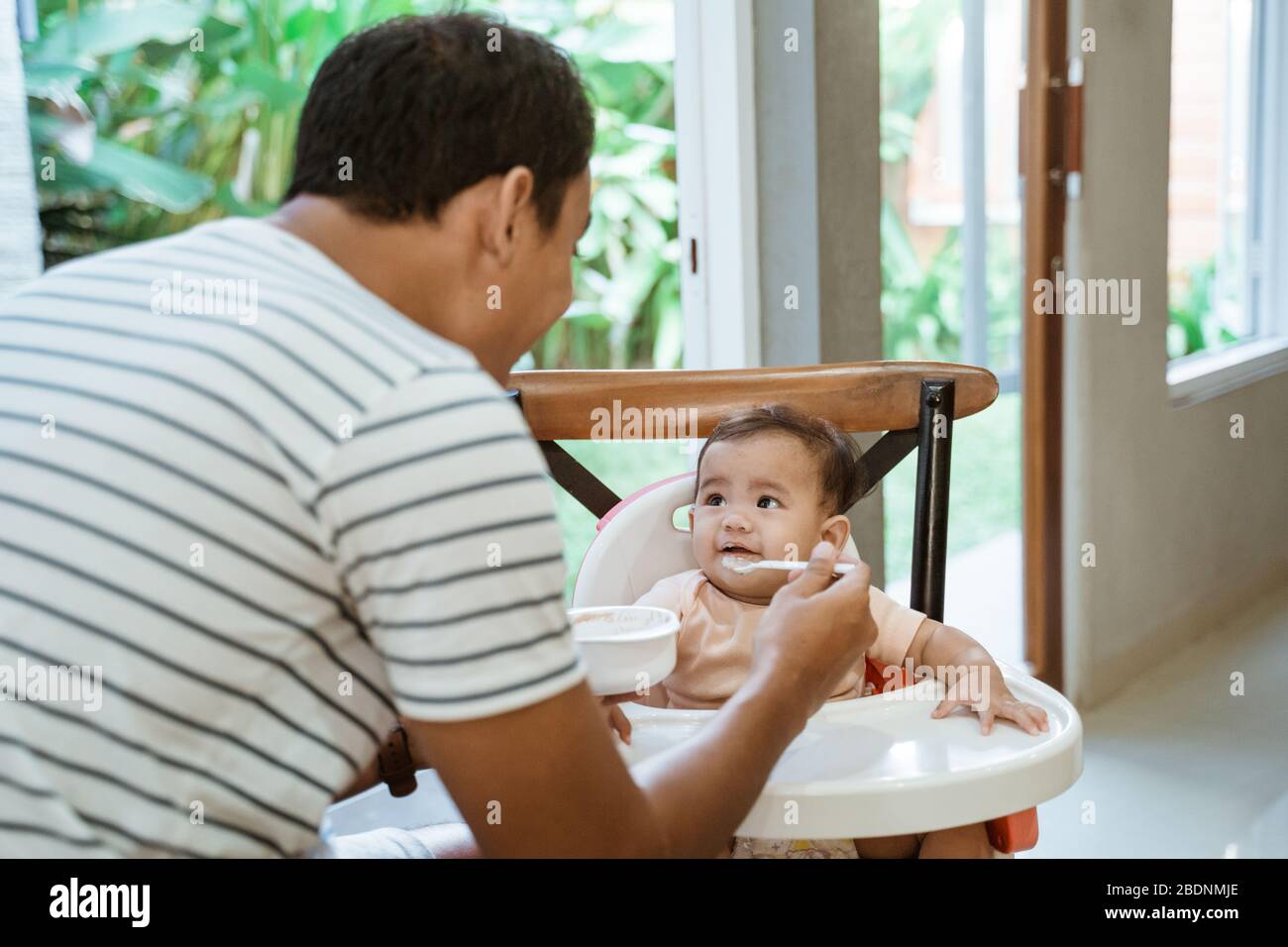 father feeding baby. meal time man taking care for his daughter Stock Photo