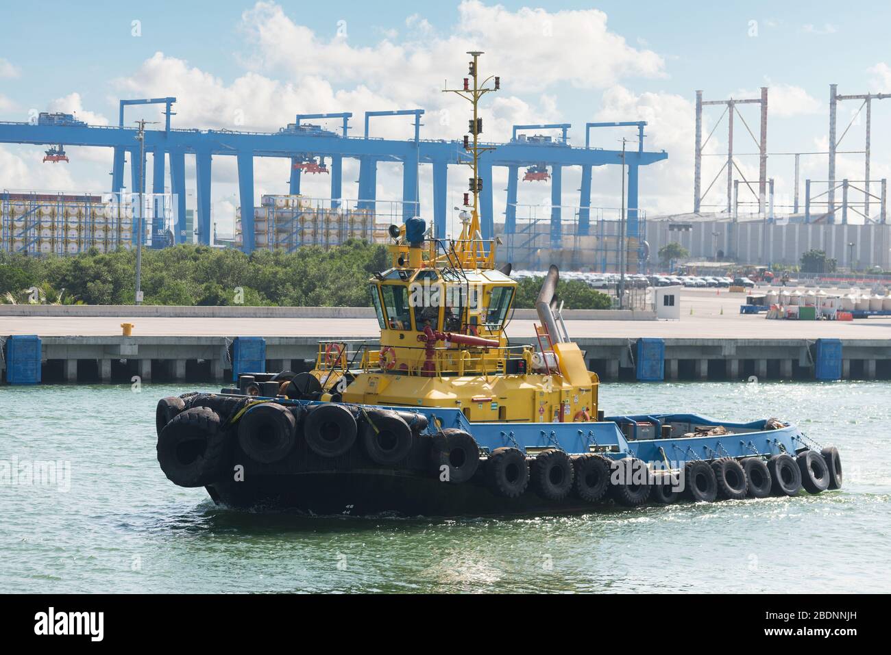 Tug boats awaiting big cargo ship in harbour for tug assistance, maneuvering, mooring operations. Tugboat and tow service concepts. Stock Photo