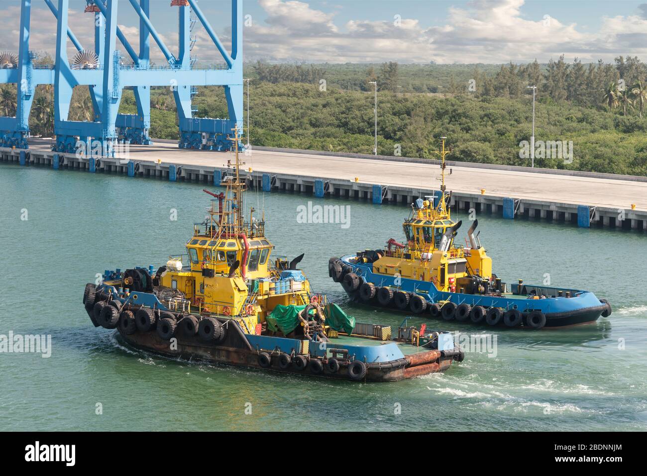 Tug boats awaiting big cargo ship in harbour for tug assistance, maneuvering, mooring operations. Tugboat and tow service concepts. Stock Photo