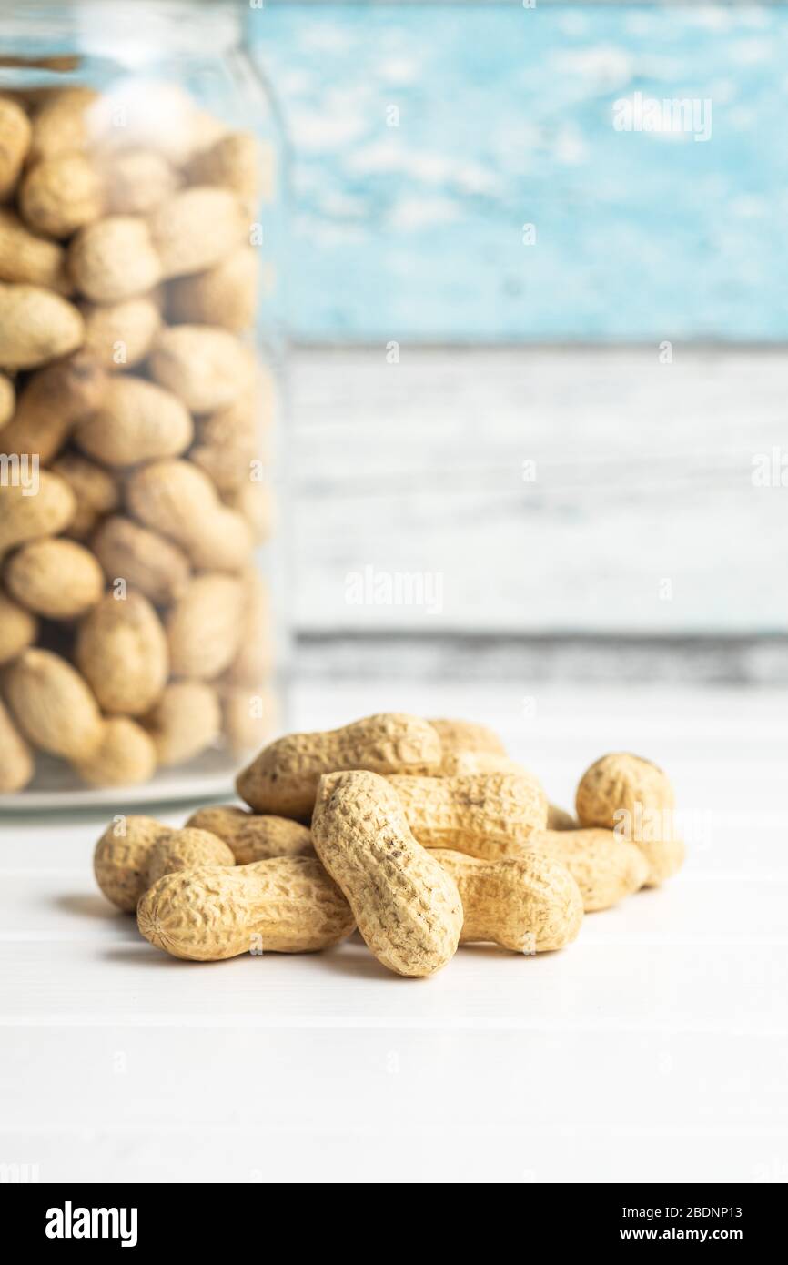 Tasty unpeeled peanuts. Peanuts in nutshell on white table. Stock Photo