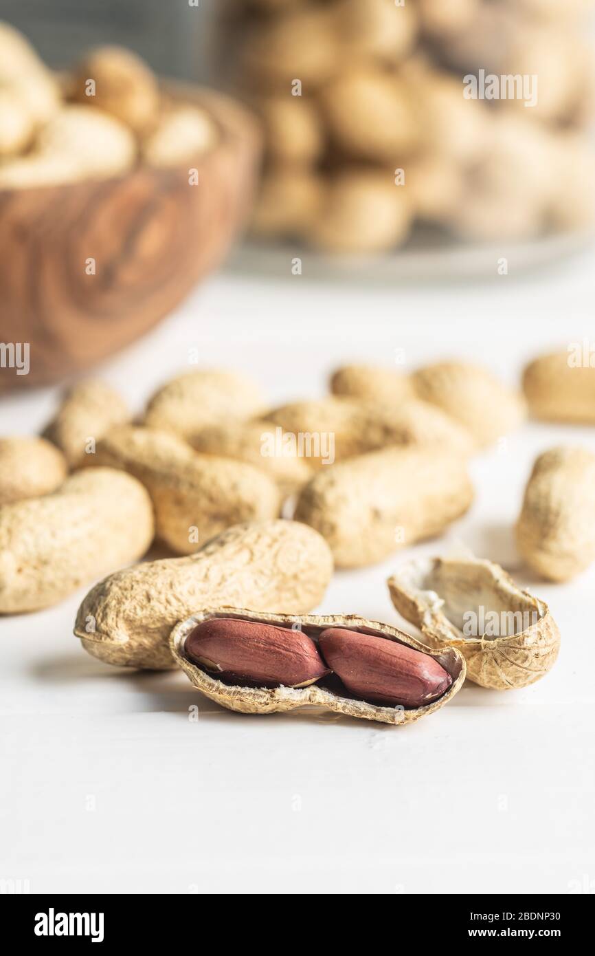 Tasty unpeeled peanuts. Peanuts in nutshell on white table. Stock Photo
