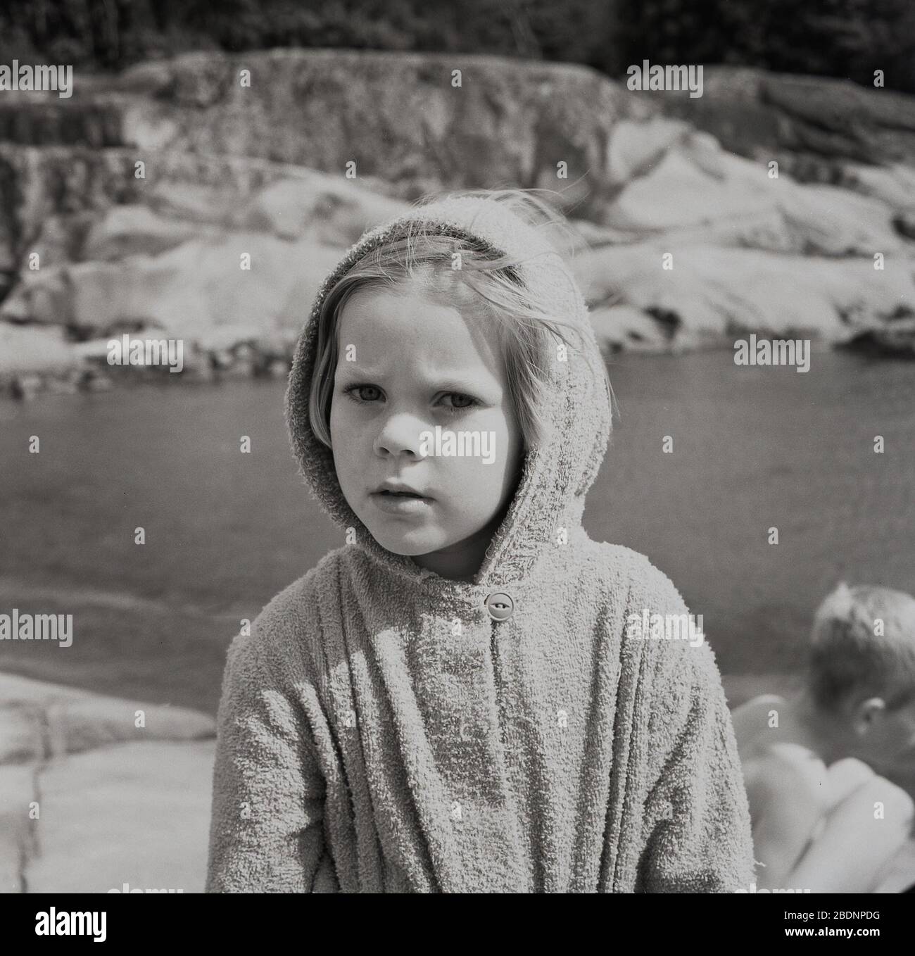 1960s, historical, young girl wearing a cotton top or poncho with hood, a popular toweling garment worn by youngsters in this era after swimming. Stock Photo