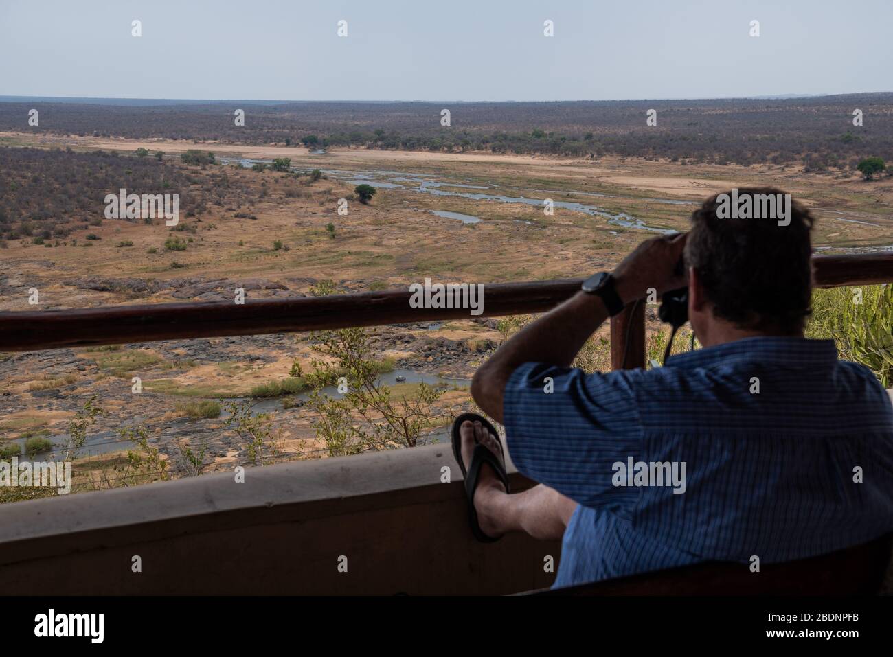 A tourist looking through binoculars in the Kruger National Park Stock Photo