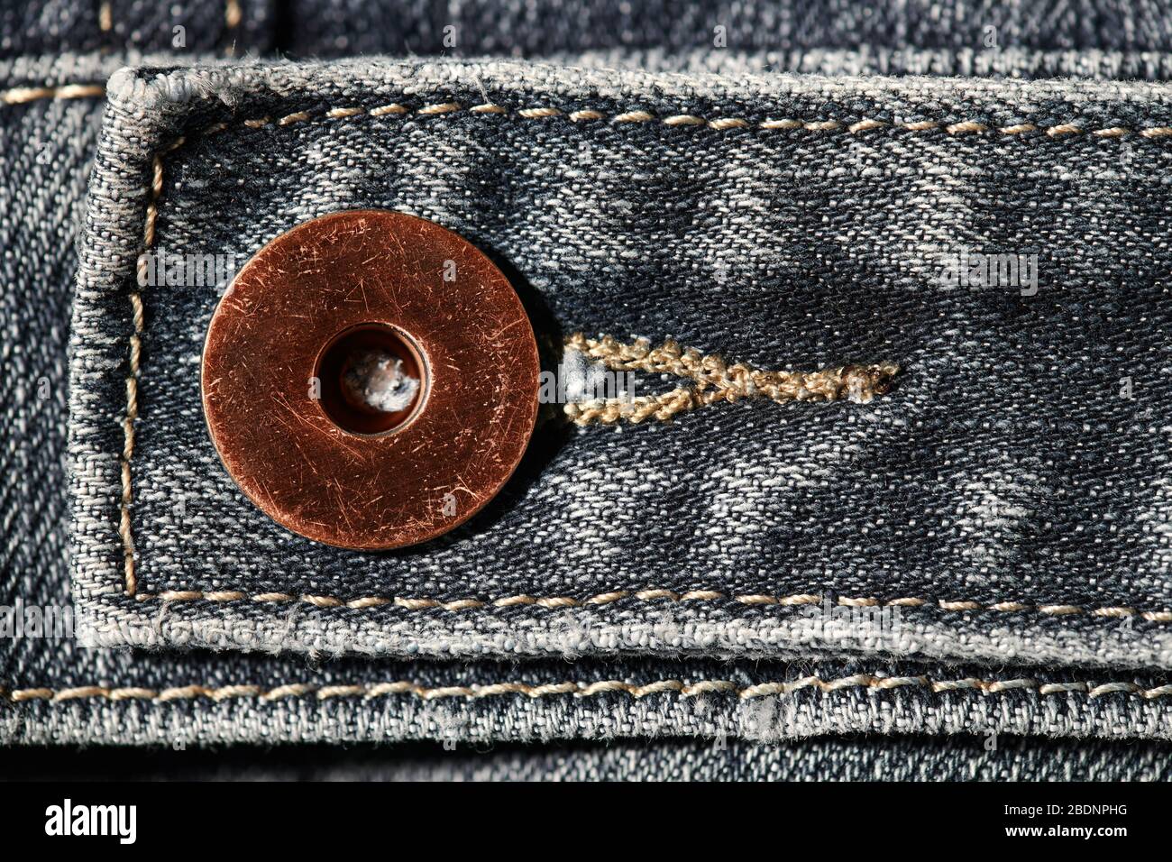 a brass button with jeans natural clean background macro photo, dark