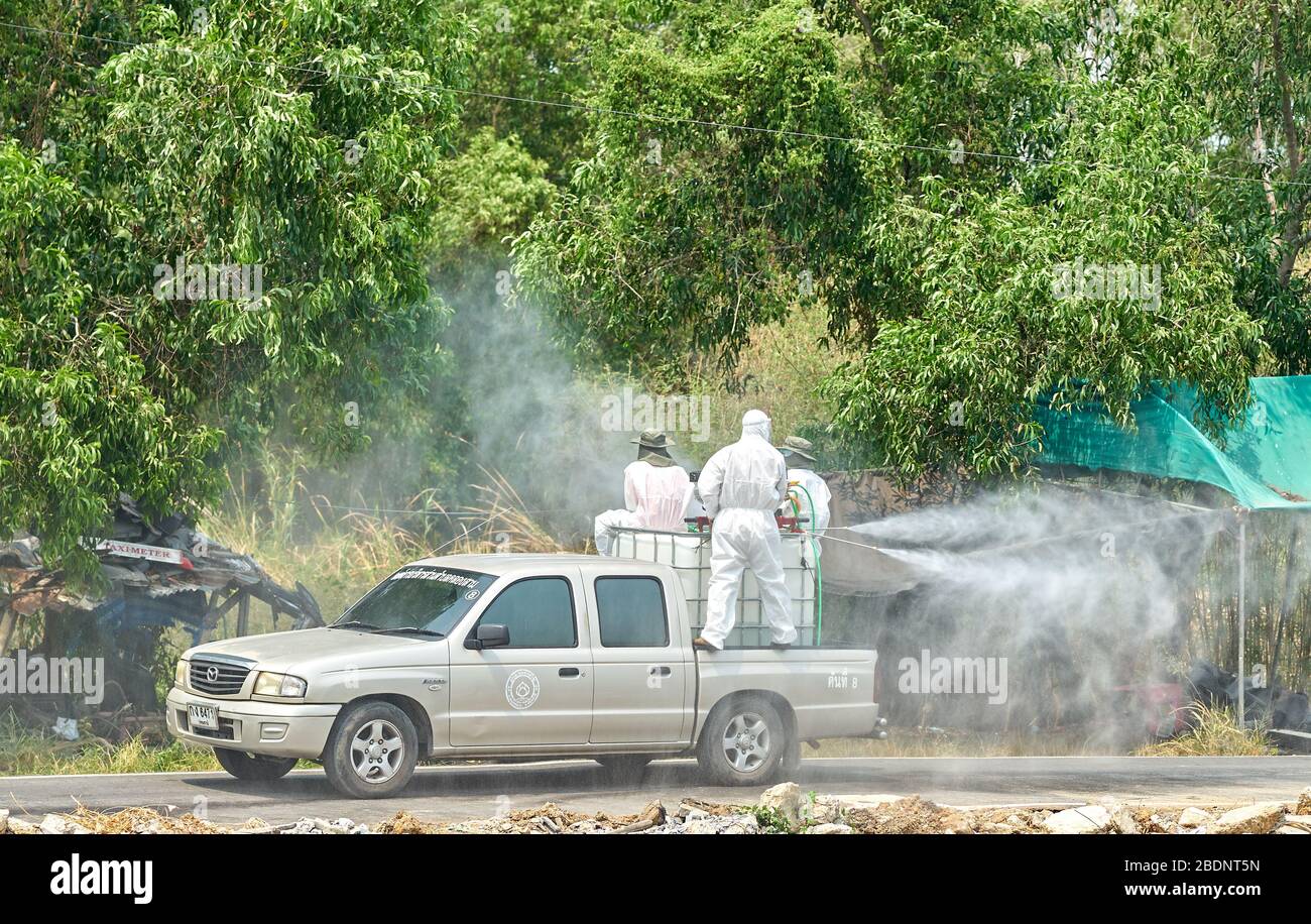 Men in white protective suits spray liquid from a pickup truck. Stock Photo