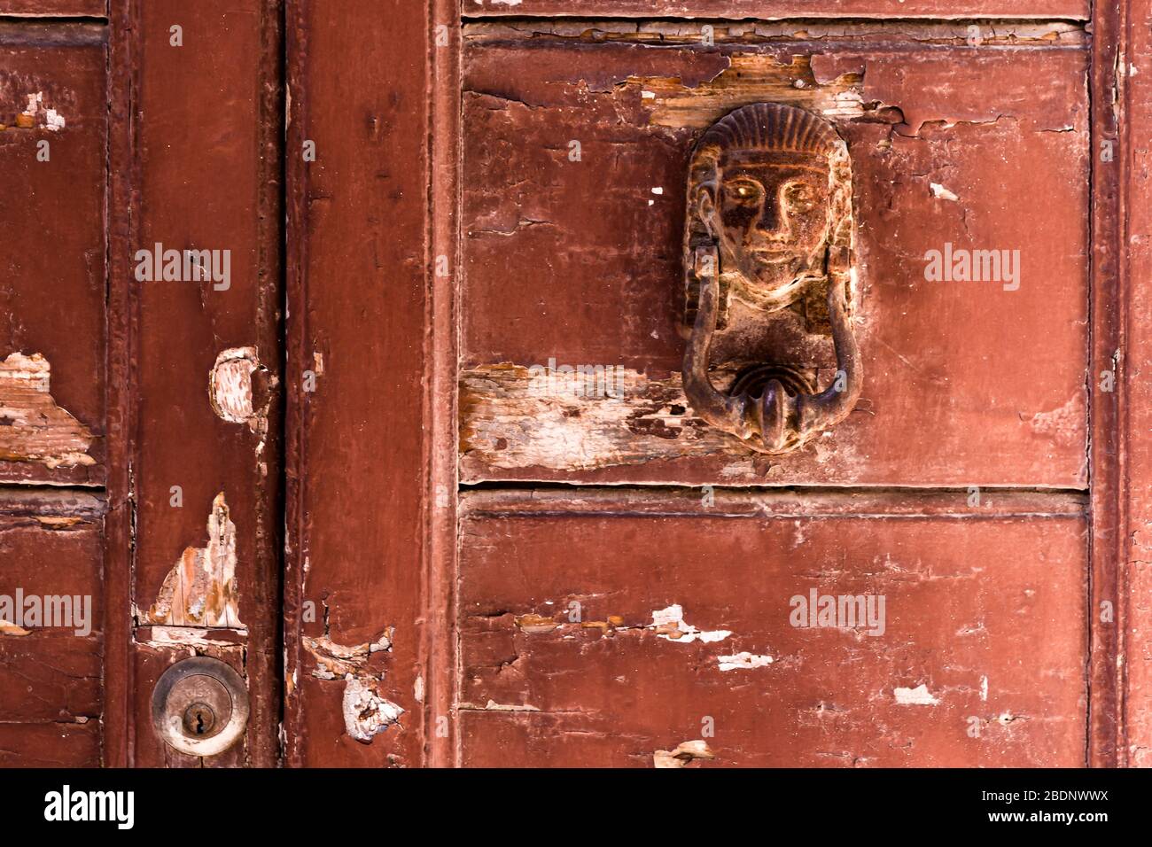 Detail of an old, weathered and rustic door with a rusty, Egyptian themed door knocker Stock Photo