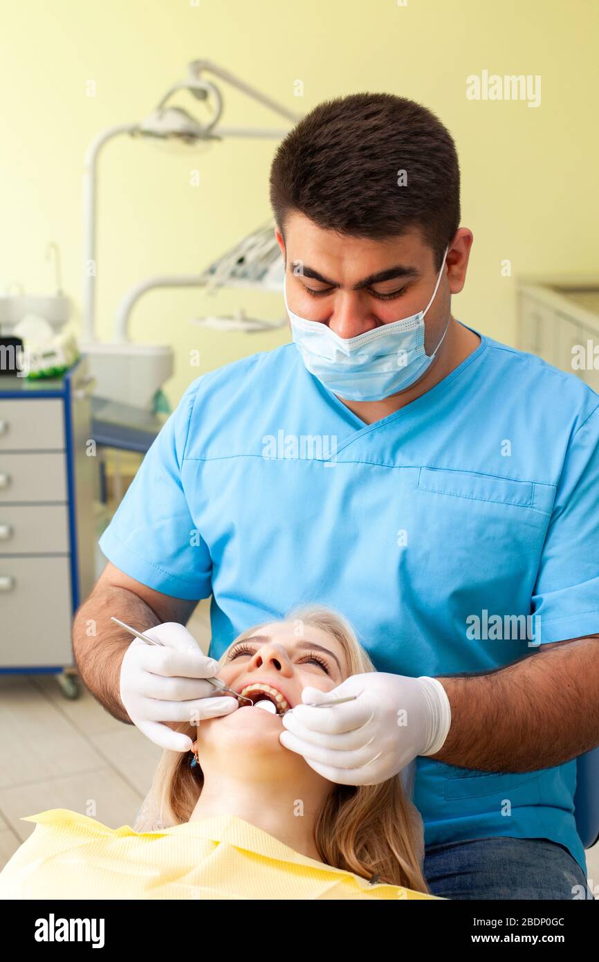 Dentist examining patient's teeth, wearing blue uniform and gloves ...