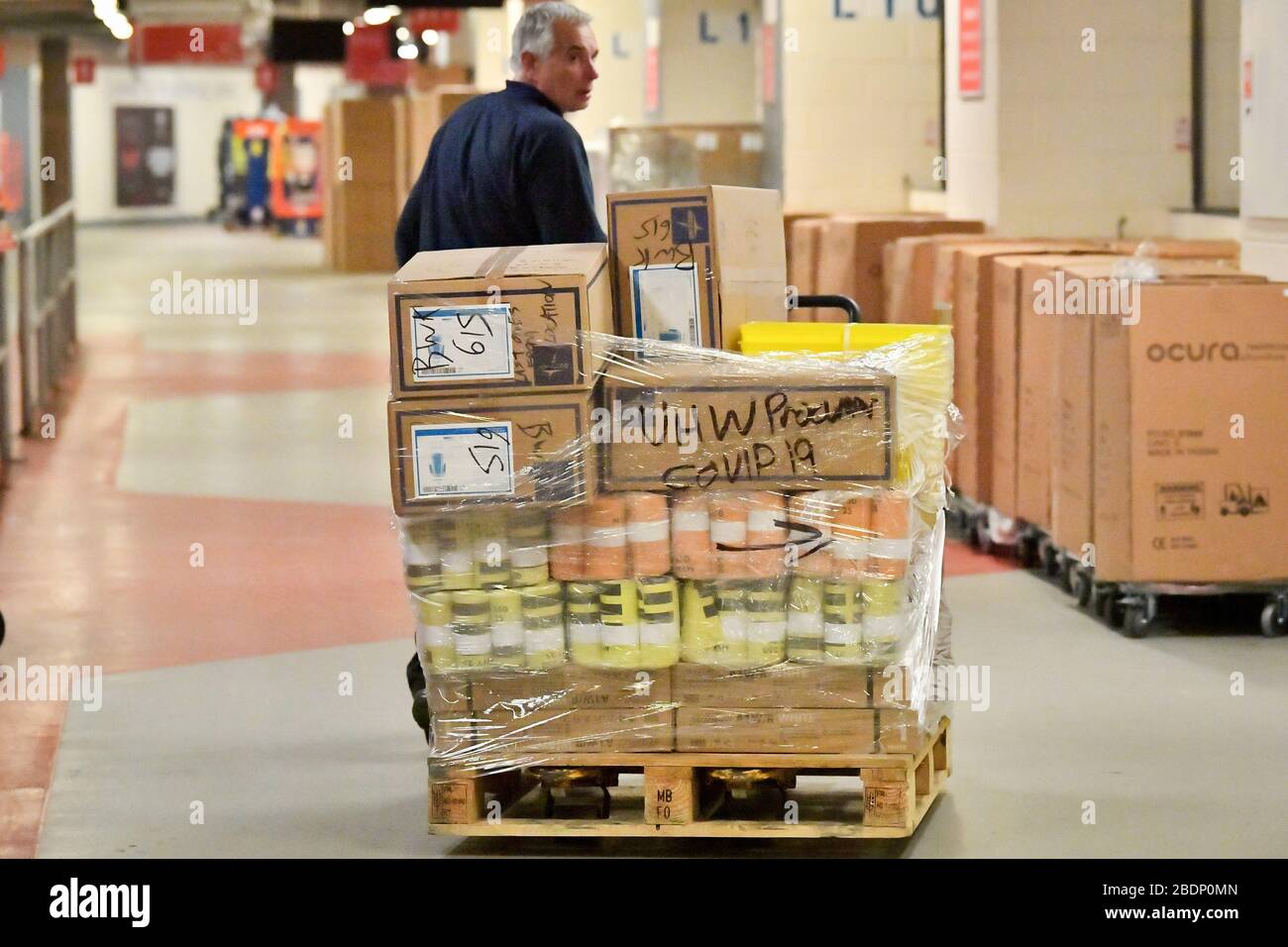 A man moves a pallet of medical supplies labeled covid-19 inside the Principality Stadium, Cardiff, which is being turned into a 2000-bed hospital to help fight coronavirus. Stock Photo