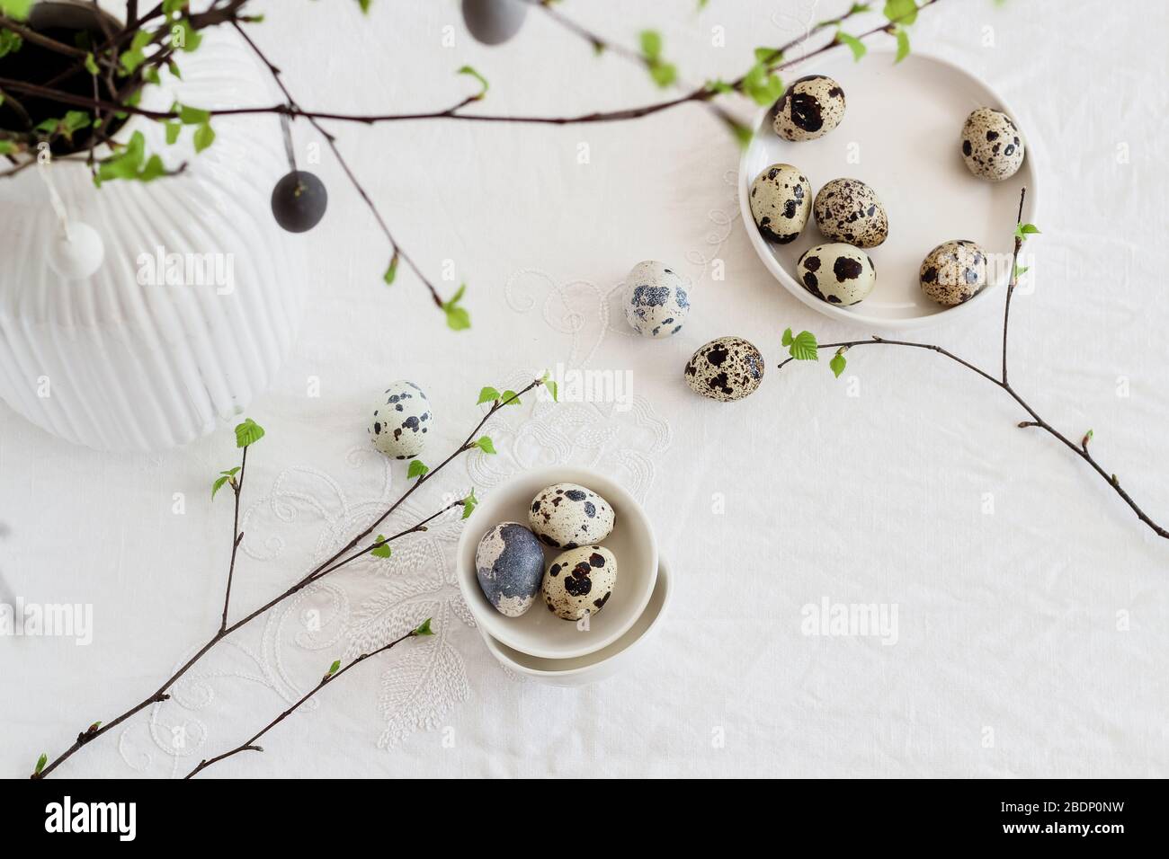 Easter table decorated with quail eggs and birch tree branches. Modern minimalistic Easter decor flat lay Stock Photo