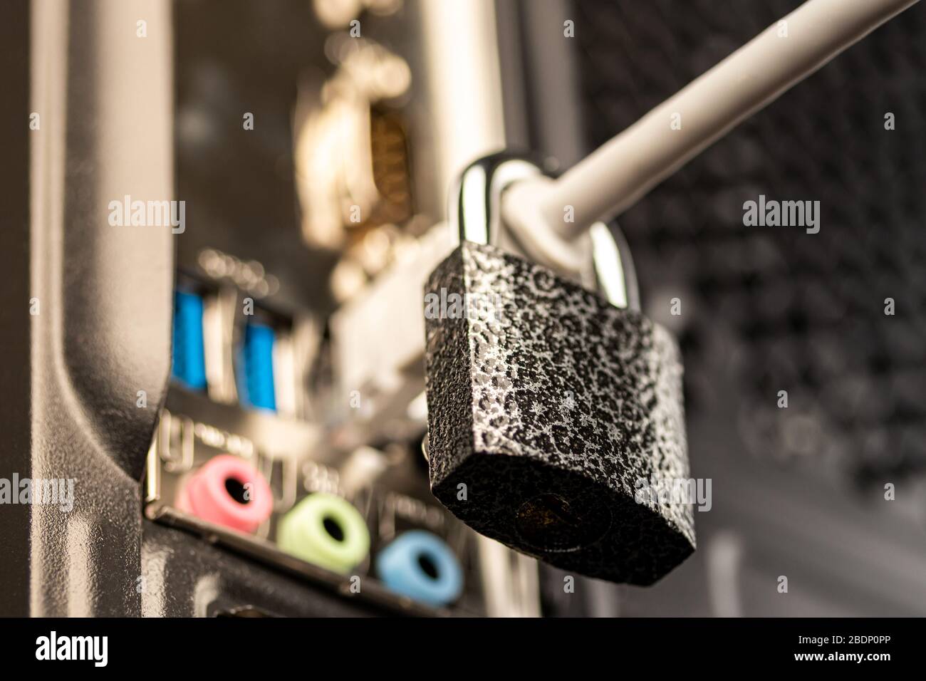 Closed lock hanging on a network cable plugged into a computer. The concept of security or blocking the Internet or the safety of personal data. Antiv Stock Photo