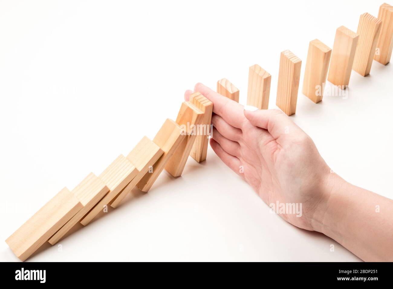 Hand stops falling wooden blocks. Crisis inhibition concept Stock Photo