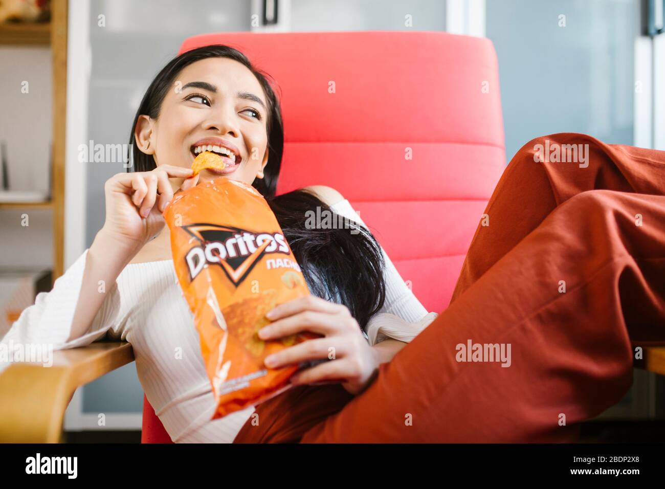 Beautiful asian woman eating Doritos. Stock Photo