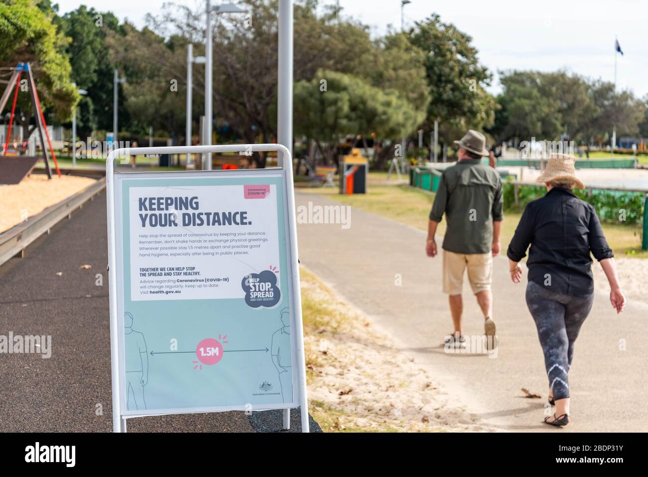 A couple walk past a sign saying 'Keep your distance' at the Southport, Gold Coast.Council has taken an extraordinary step of closing some Gold Coast beaches as a preventive measure against the spread of Coronavirus after thousands of people ignored social distancing rules. Beaches at The Spit, Surfers Paradise and Coolangatta will shut from midnight. The remainder of the city’s beaches will stay open for people to exercise, swim or surf, but Council says it won’t hesitate to close more beaches if people continue to flout the rules. Stock Photo