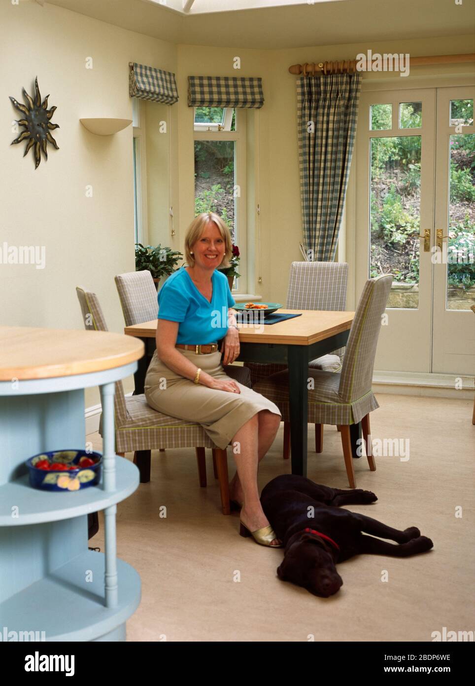 Woman relaxing with black labrador in diningroom FOR EDITORIAL USE ONLY ...