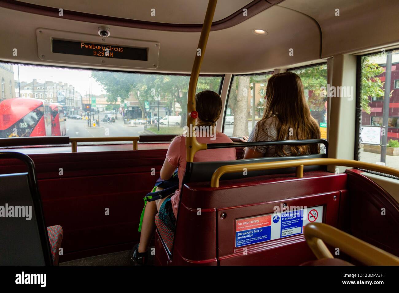 Two young girls sit at the front on the top deck of a double decker bus in London, England. Stock Photo