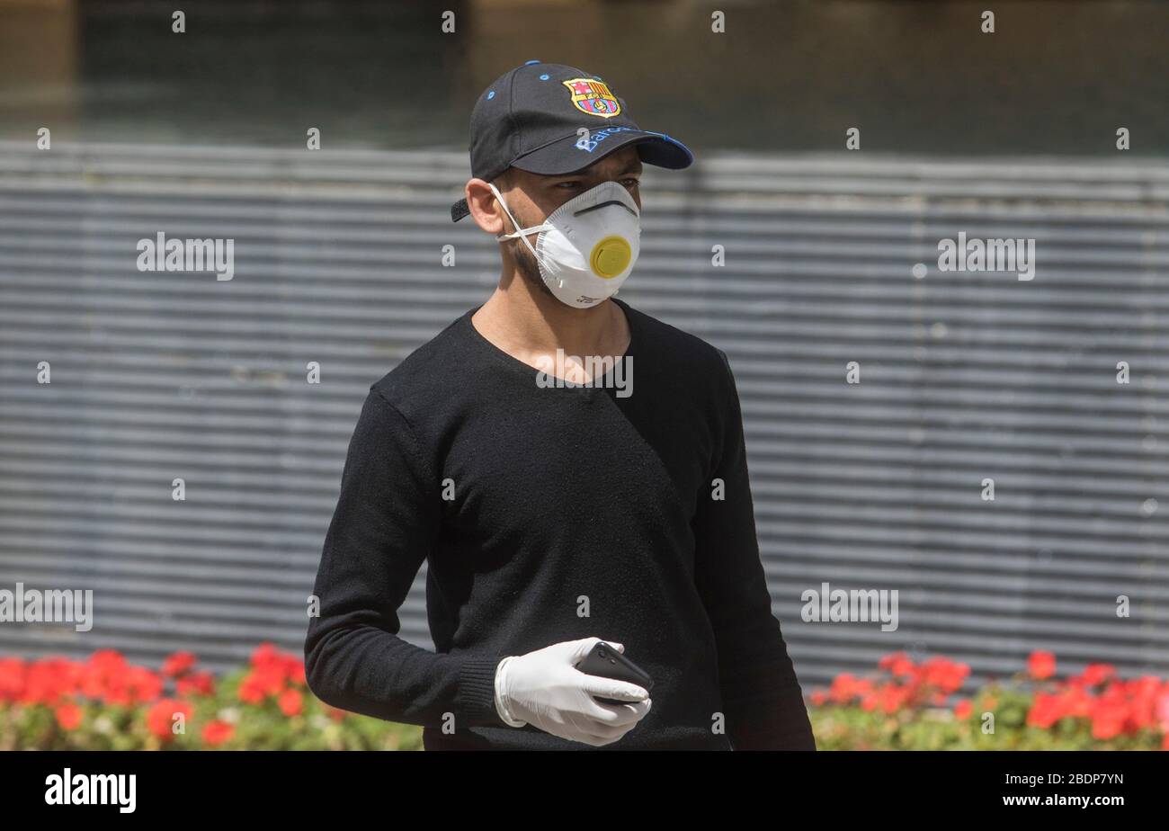 Beirut, Lebanon. 9 April 2020. A pedestrian in a FC Barcelona baseball cap  wearing a protective surgical mask with a FC Barcelona cap. The Lebanon  government has ordered residents to stay at