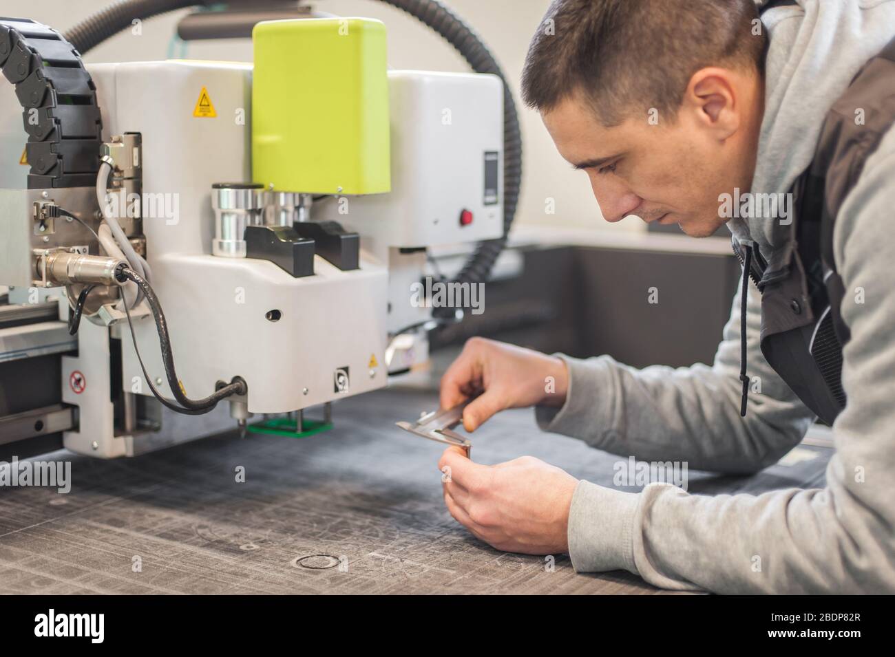 Electrical engineer repairs a knife cutting head on large CNC computer numerical control printing and cutting machine Stock Photo