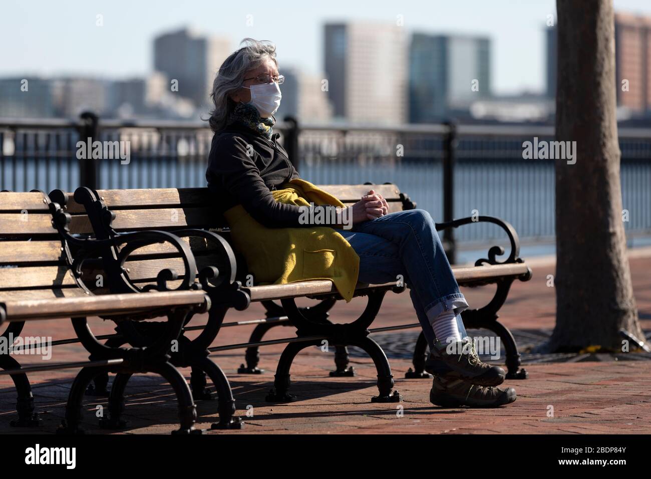 Woman wearing a face mask while sitting on a bench in Piers Park
