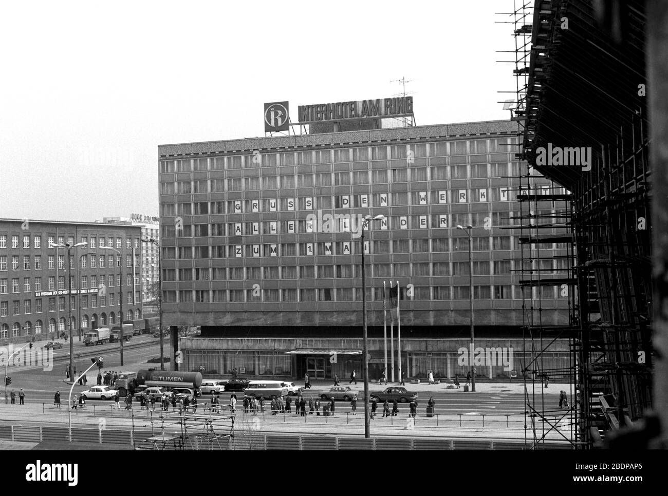 15 April 1980, Saxony, Leipzig: In front of the construction site 'Neues Gewandhaus Leipzig' the appearance of the Karl-Marx-Platz in April 1980 with its old and newly constructed buildings is visible. The picture shows the Interhotel 'Am Ring' with the lettering 'Greetings to the working people of all countries on 1 May'. Exact date of photograph not known. Photo: Volkmar Heinz/dpa-Zentralbild/ZB Stock Photo