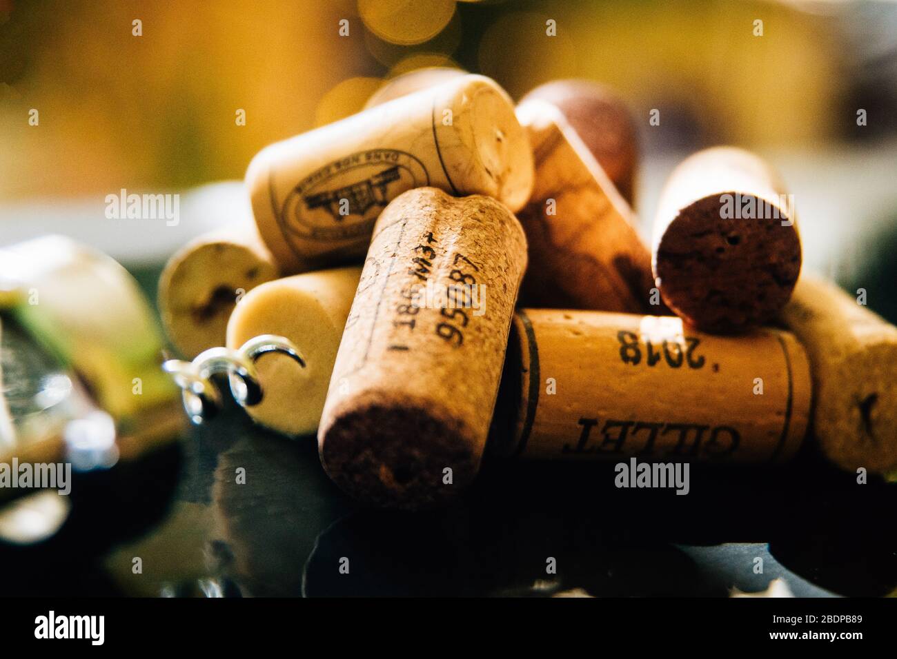 A pile of corks and a corkscrew close up on slate. Shallow depth of field with bokeh in background Stock Photo