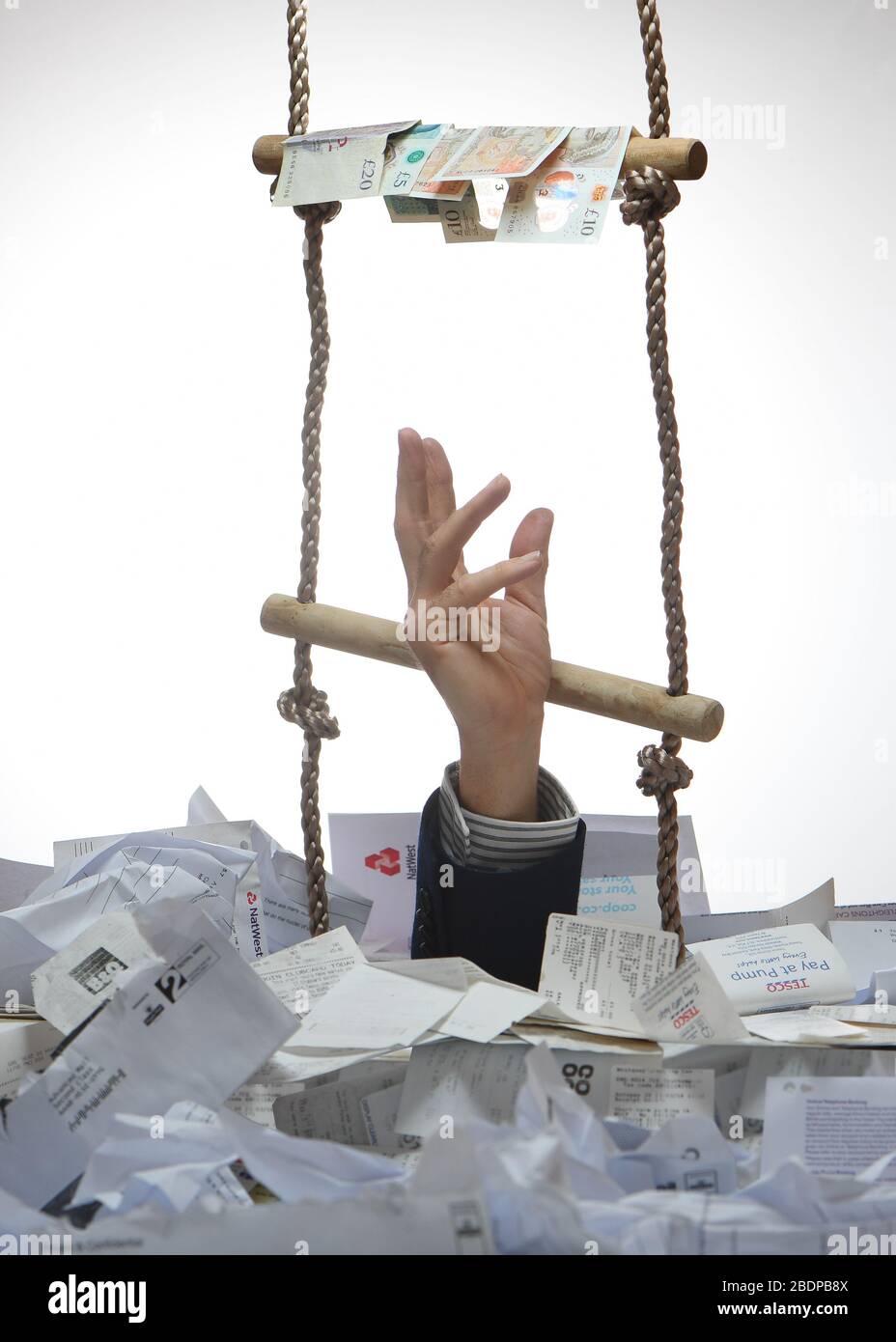 A business concept image of a rope ladder coming out of a pile of receipts with a hand reaching for money ignoring ladder. Stock Photo