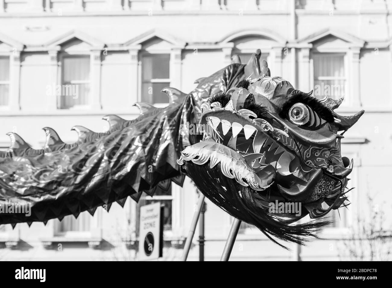 Up close with the vivid orange coloured dragon as it dances through the streets of Liverpool's Chinatown district during the new year celebrations. Stock Photo