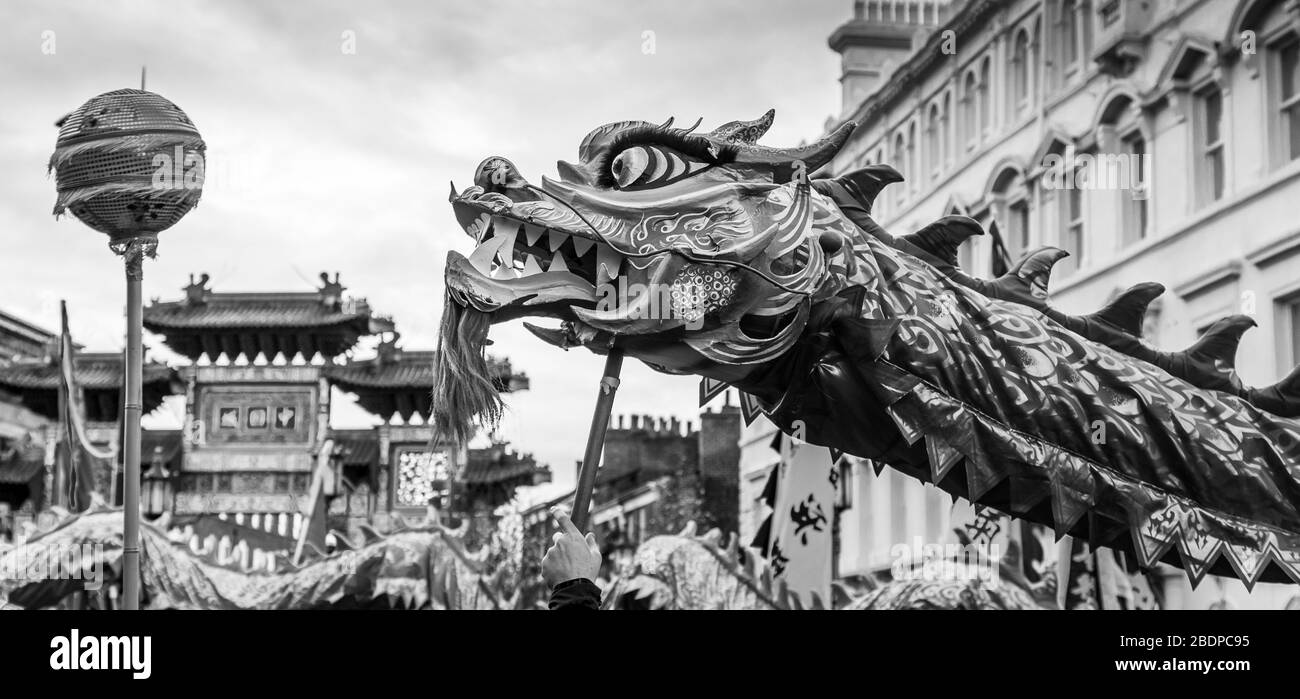 The pretty orange and red coloured dragon weaves through the crowds of people in Liverpool's Chinatown chasing a pearl during Chinese New Year celebra Stock Photo