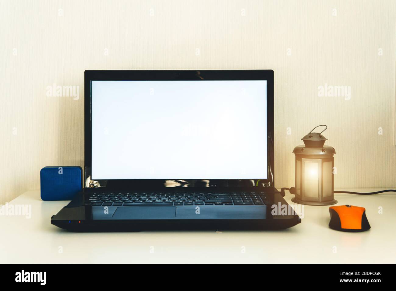 Home office workplace. Work from home. Notebook, bluetooth speaker and nice lamp on the table. Freelance, work at home or quarantine concept. Stock Photo